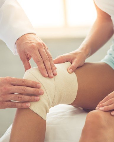 Doctor bandaging patient's knee, injury recovery