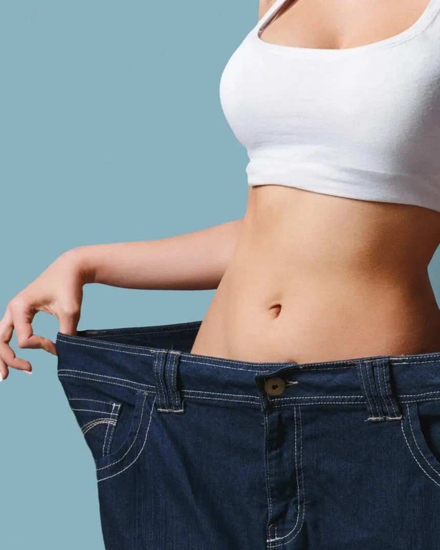 Woman showing weight loss in oversized jeans